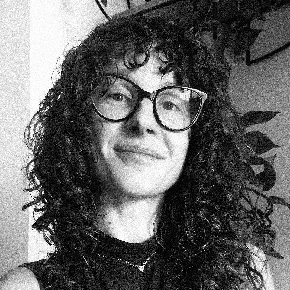 Anastasia Fratus, ritratto in bianco e nero, capelli ricci e occhiali, sorridente